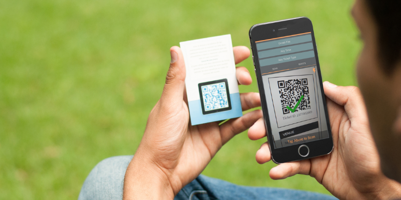 Young man scanning a QR code with Passage Manager app on his mobile phone while sitting outdoors