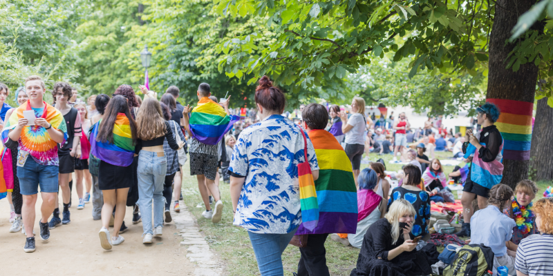 People wearing rainbow flags at an outdoor pride event