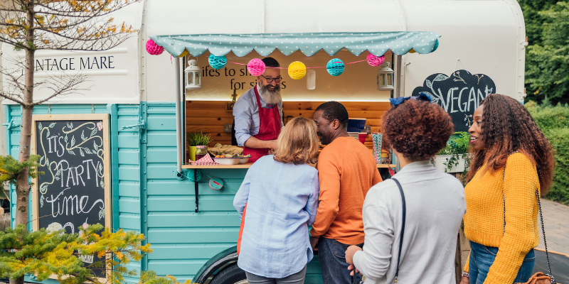 Outside guests walking up to order from a vegan food truck beautifully decorated