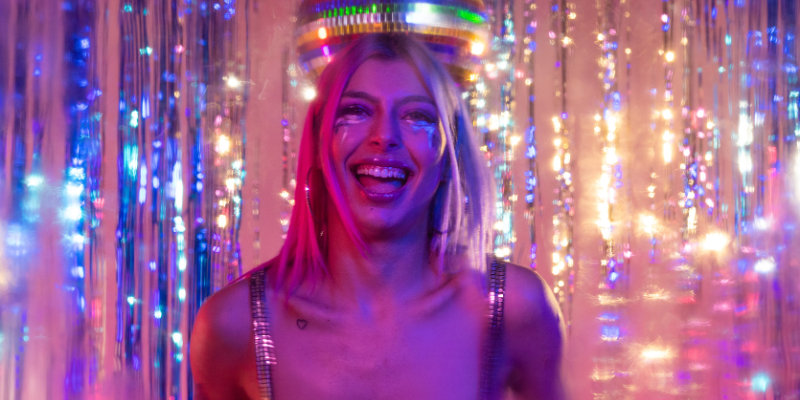 Woman at a party in 2000s style makeup against a sparkly party backdrop