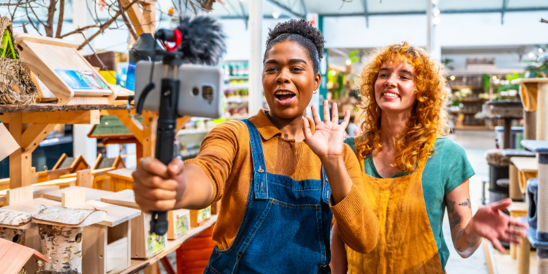 Two saleswomen filming a social media video inside their shop