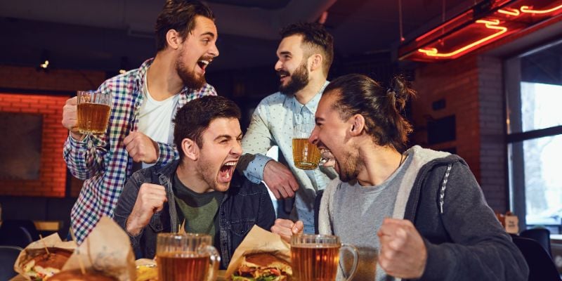 4 men cheering at a bar