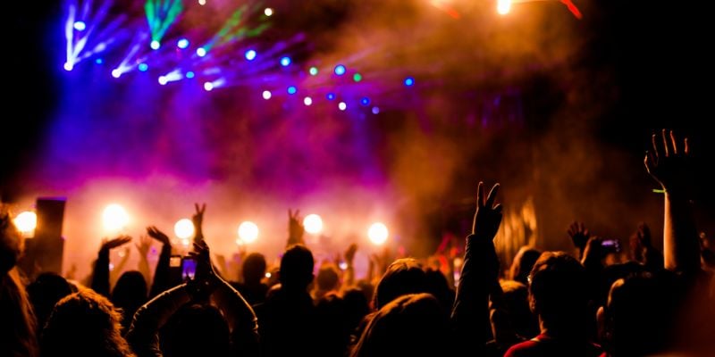 crowd watching a concert with laser lights and fog