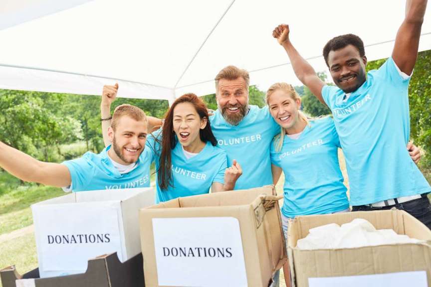 volunteers cheering with donation boxes on table