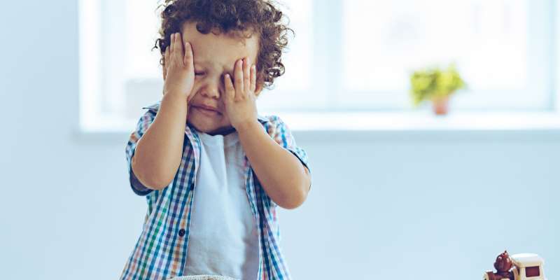 toddler with face in hands upset