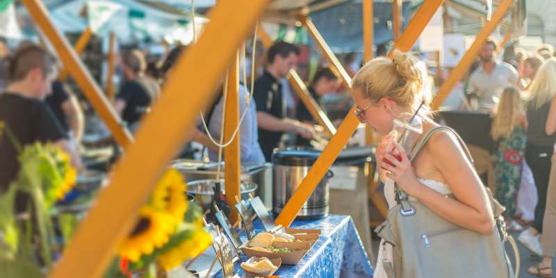 person holding an ice coffee while deciding what to eat at an outdoor festival