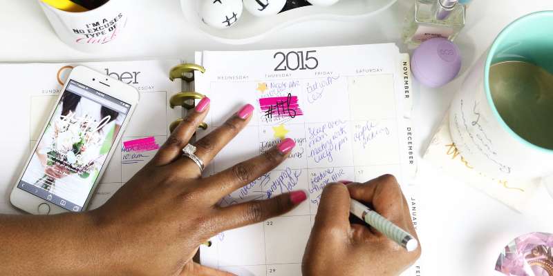 planner with calendar; hands with painted nails writing