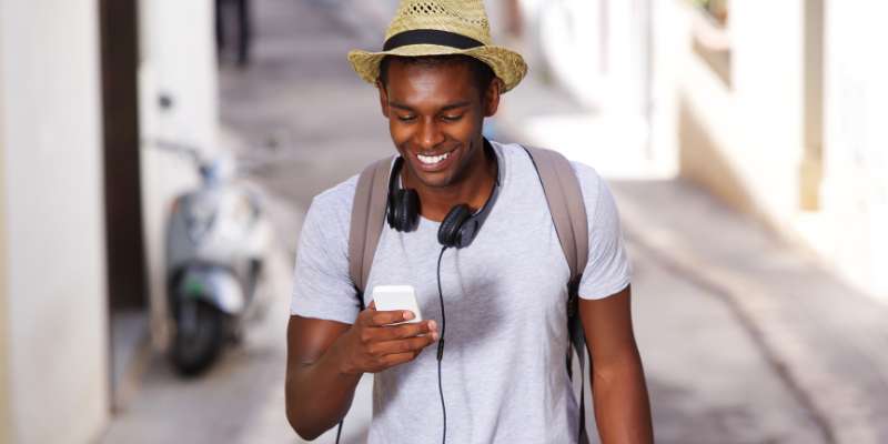 happy guy wearing hat using cell phone