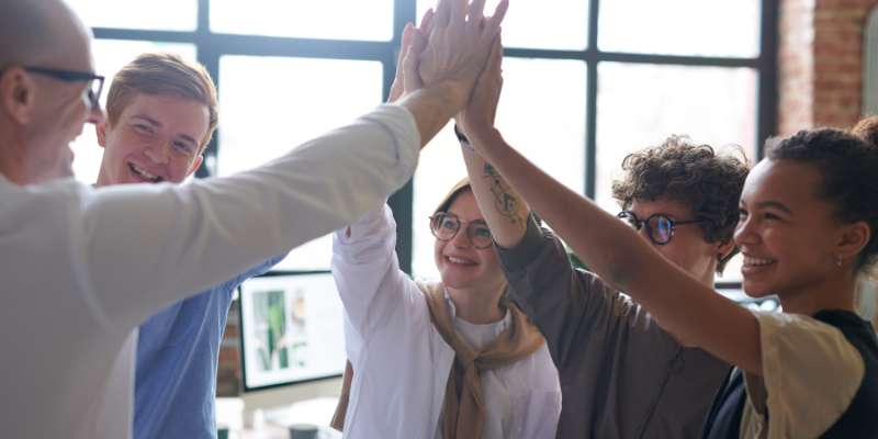 team of people group high-fiving in conference room