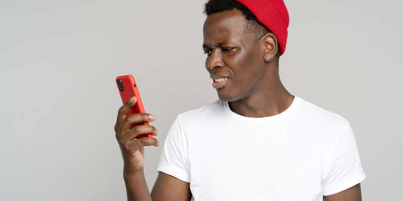 unhappy man in red hat looking at (red) phone with digust
