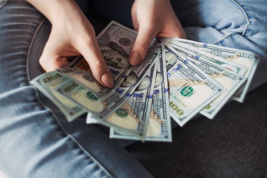 person fanning out a handful of $100 bills