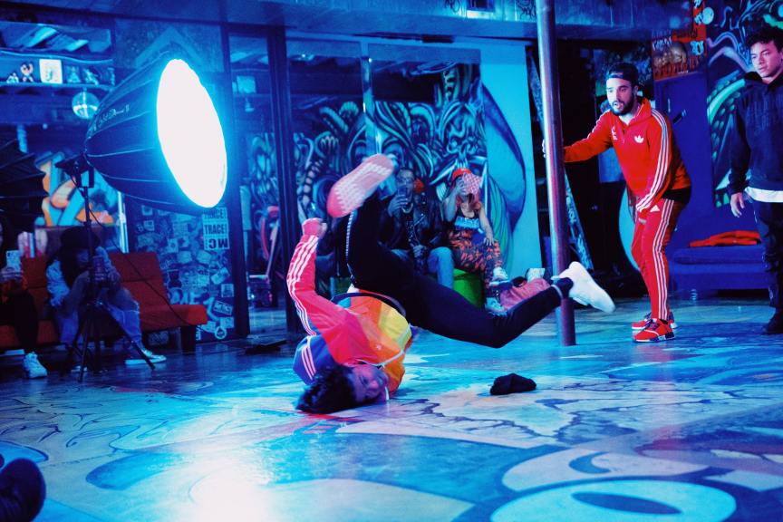 two men filming a breakdancing video in graffiti filled room
