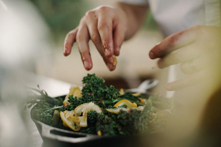 Person's hands putting the finishing touches on a kale and lemon salad