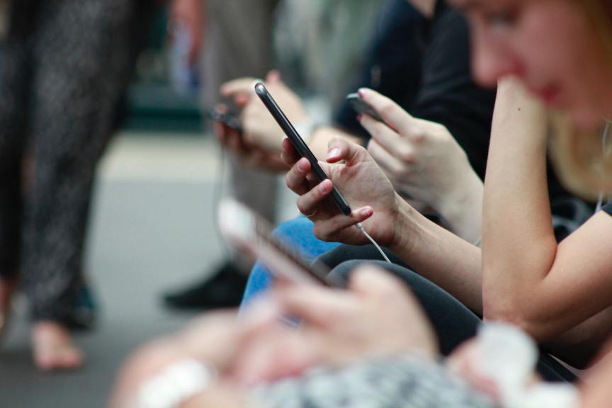 young people sitting in a row using their mobile phones