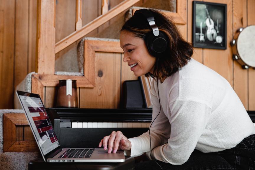 woman with short brown hair wearing headphones using laptop next to a keyboard