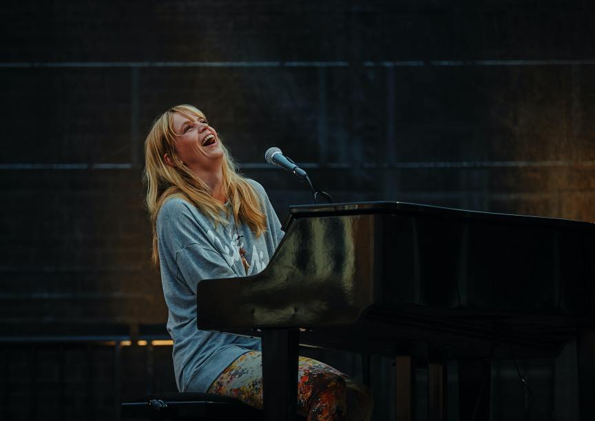 blonde haired woman singing while playing piano