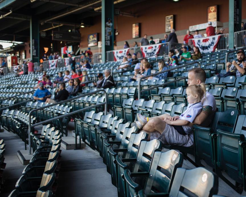 fans sitting in a half-empty baseball stadium