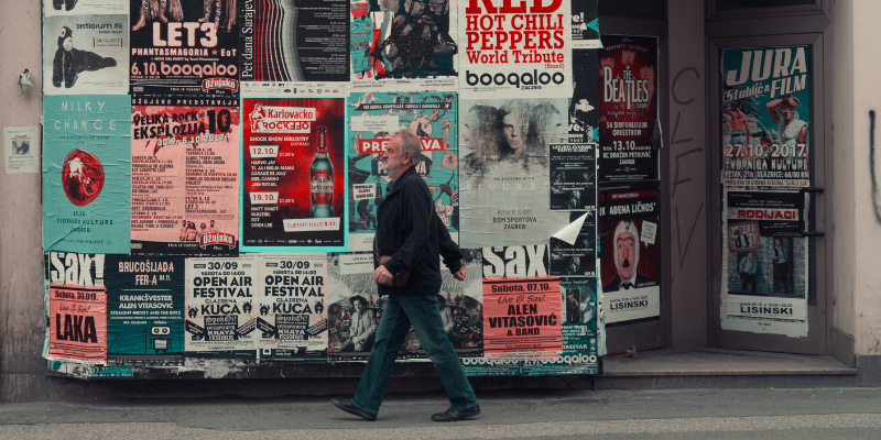 Man walks in front of a wall of posters