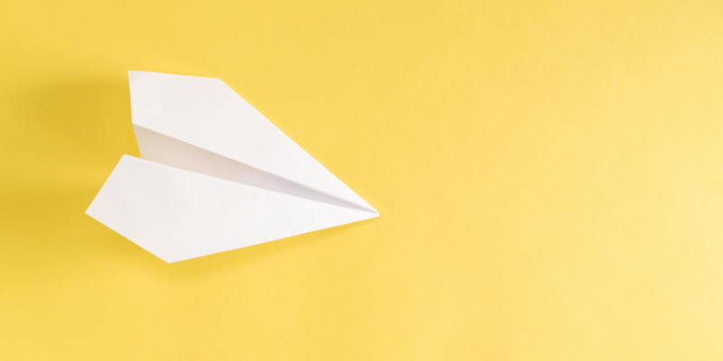 White paper airplane with yellow background