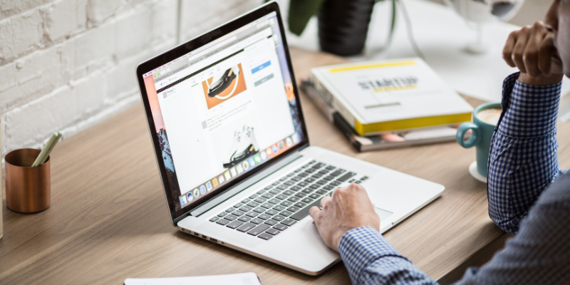 Man looking down at a laptop screen with a website open.