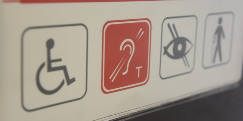 Four accessibility symbols with one being red and more in focus. 