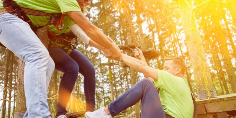 Trained staff helping guest up after ziplining