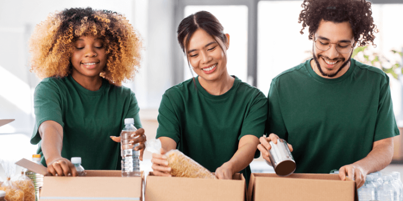 Three people loading up boxes with non-perishable foods at a food drive.