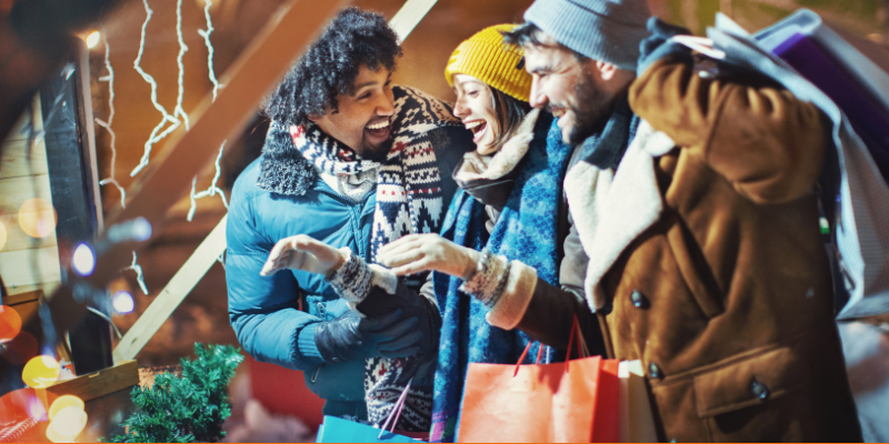 Closeup side view of multi-ethnic group of adults buying souvenirs at a Christmas market 