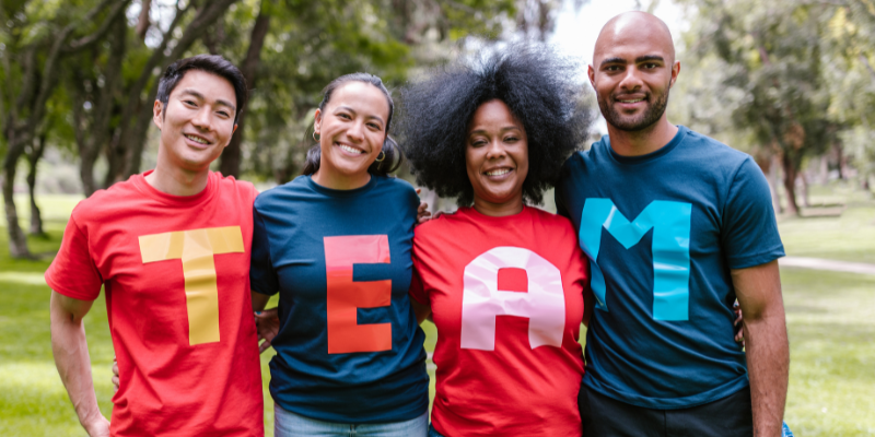 Group of diverse people wearing shirts that spell out the word TEAM