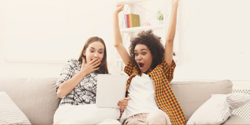 Two Happy excited female friends using digital tablet