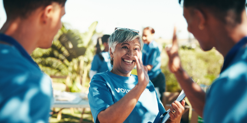 Volunteers high five each other outdoors at fundraising event