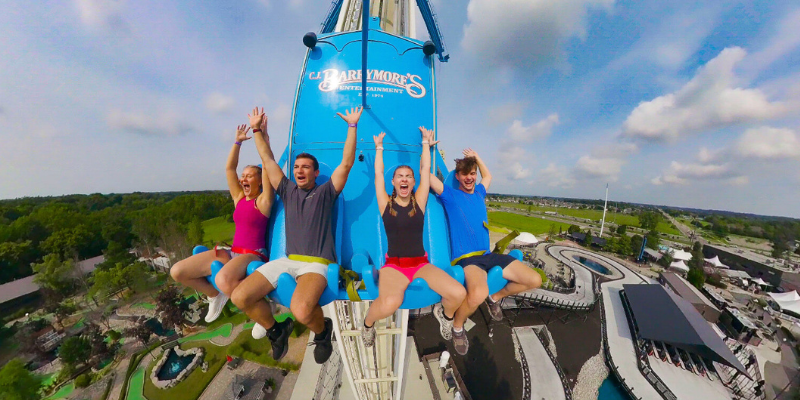 Four friends raising hands in the air and shouting with delight while riding the Hammerhead Drop at C.J. Barrymore's