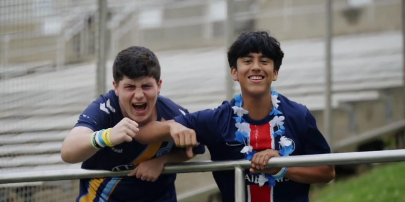 Two Chattanooga FC fans wearing team jerseys cheering on their team while looking into the camera