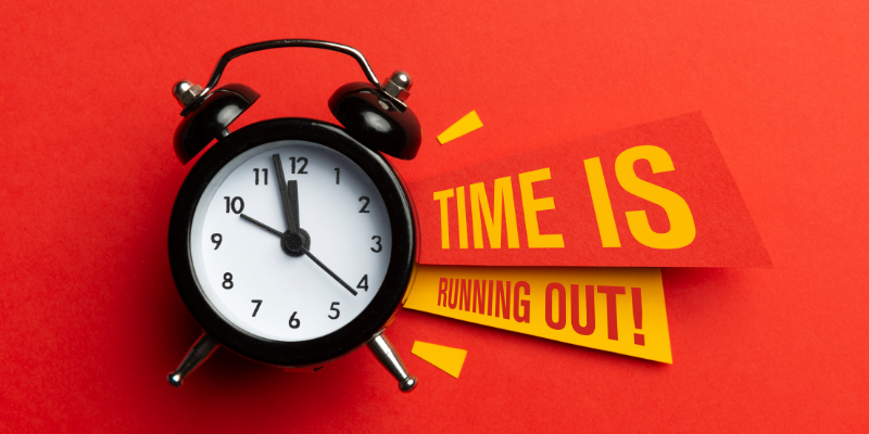 Alarm clock and color papers on a red background with the words time is running out