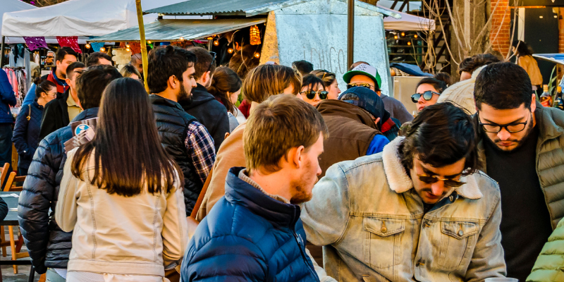 Crowd of people wearing fall jackets attending an outdoor street fair