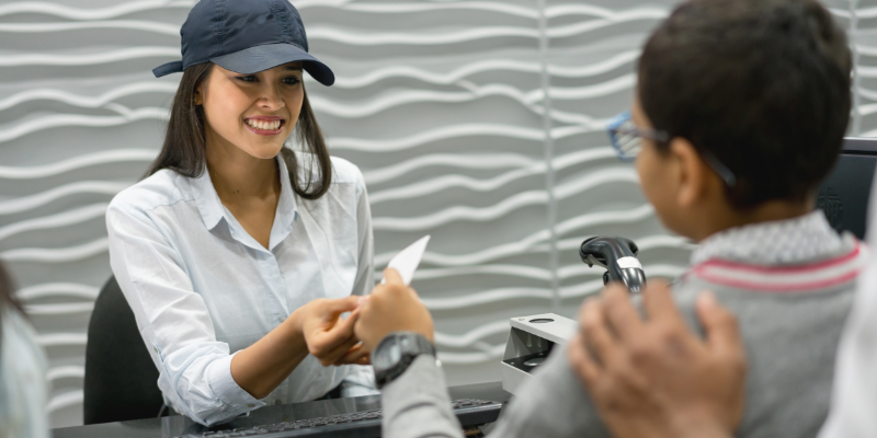 Happy woman in baseball cap selling tickets at a venue entrance