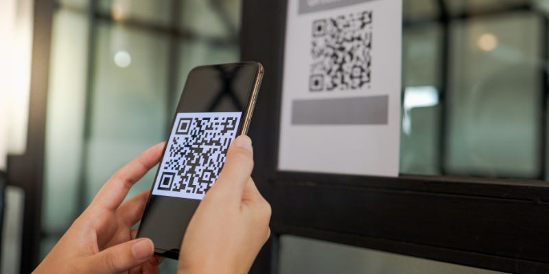 Close-up shot of a person scanning a qr code on a paper sign with their mobile phone