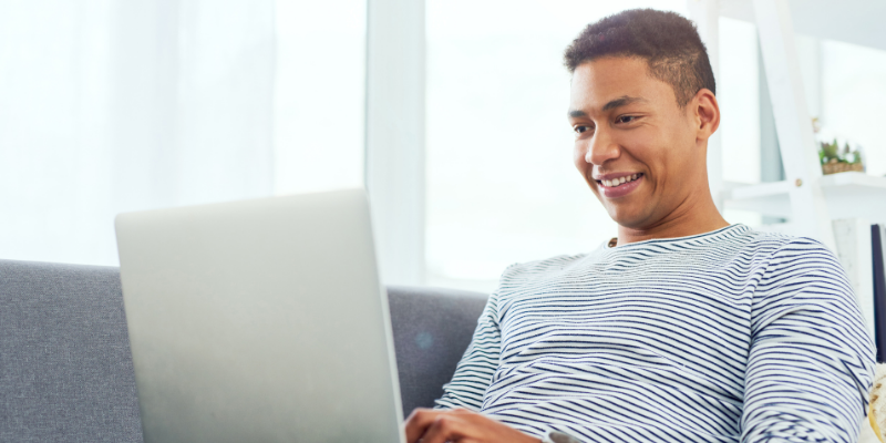 Young man using a laptop while relaxing at home