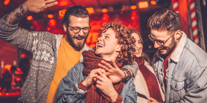 Four people smiling and laughing with each other while wearing winter apparel.