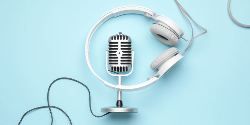 Silver microphone with white headphones in front of a plain blue background